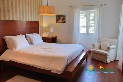 a bedroom with a large bed and a chair at OurMadeira - Casa do Júlio in Calheta