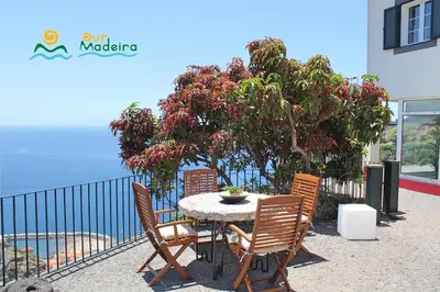 a table and chairs with a view of the ocean at OurMadeira - Casa do Júlio in Calheta
