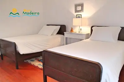 a room with two beds and a sign on the wall at OurMadeira - Casa do Júlio in Calheta