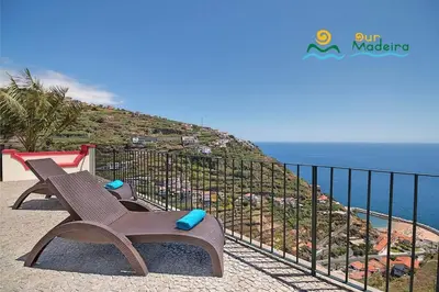a wooden bench sitting next to the ocean at OurMadeira - Casa do Júlio in Calheta