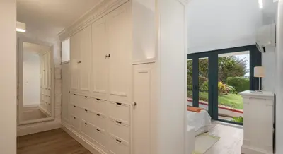 a dressing room with white cabinets and a large window at OurMadeira - Villa do Mar I in Arco da Calheta