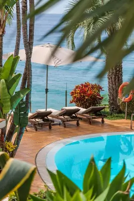 a pool with two lounge chairs and an umbrella at OurMadeira - Villa do Mar I in Arco da Calheta