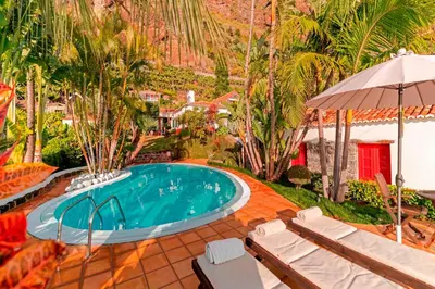 an outdoor swimming pool with chairs and an umbrella at OurMadeira - Villa do Mar I in Arco da Calheta