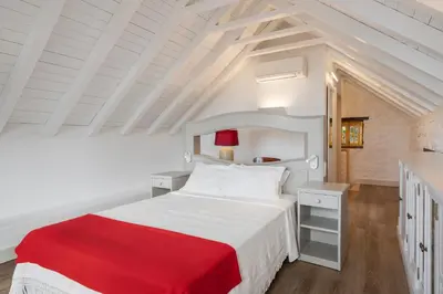 a bedroom with a white bed with a red blanket at OurMadeira - Villa do Mar I in Arco da Calheta