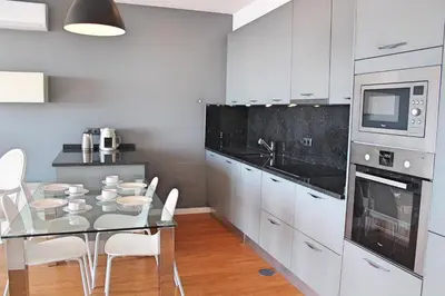 a kitchen with a glass table and white cabinets at OurMadeira - Vila da Portada in Funchal