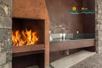 a bathroom with a fireplace with a sink and a fire at OurMadeira - Cliffscape in Estreito da Calheta