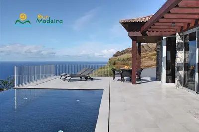 a patio with a table and benches and the ocean at OurMadeira - Cliffscape in Estreito da Calheta
