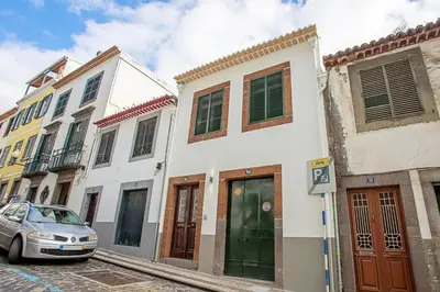 a row of buildings on a street with a car at Cayres Suites Surdo in Funchal