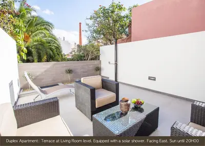 a patio with wicker furniture and a table and chairs at Cayres Suites Surdo in Funchal