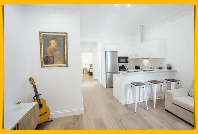 a white kitchen and living room with a guitar at Cayres Suites Surdo in Funchal