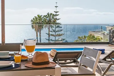 a table with a hat and glasses of orange juice at NEW! Villa Alvinho| Lifestyle&Nature | Heated Pool in Funchal