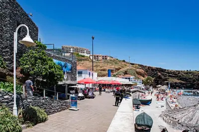a beach with a group of people sitting on the sand at Reis Magos II by An Island Apart in Caniço