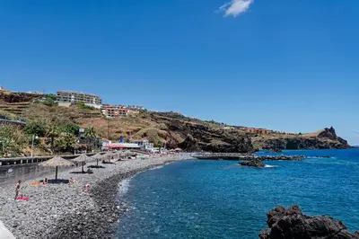 a beach with umbrellas and chairs and the water at Reis Magos II by An Island Apart in Caniço