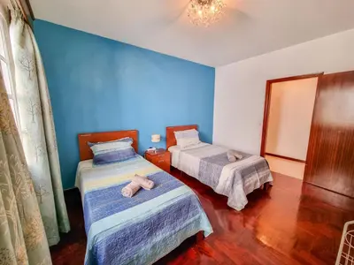 a bedroom with two beds and a blue wall at Casa da Achada in Arco da Calheta in Arco da Calheta