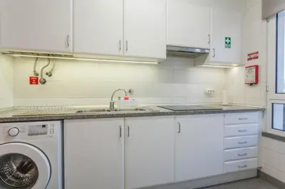 a kitchen with white cabinets and a washing machine at Blue Sky in Funchal