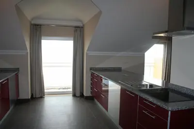 a kitchen with red cabinets and a large window at Hotel Apartamentos Baia Brava in Gaula