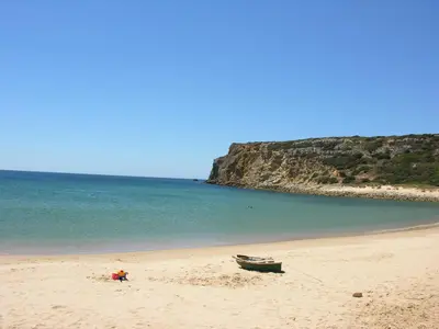 a boat on a sandy beach next to the ocean at Hotel Mira Sagres in Vila do Bispo