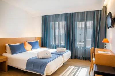 a bedroom with two beds with blue pillows at Hotel Mira Sagres in Vila do Bispo