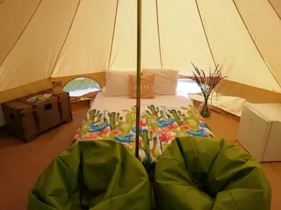 a bed in a tent with two green chairs at Granny's farm in São Vicente