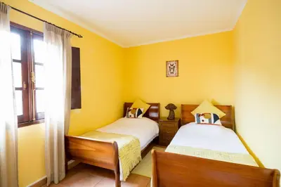 two beds in a room with yellow walls at Cantinho Rural in Camacha