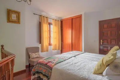 a bedroom with a bed and a chair and a window at Cantinho Rural in Camacha