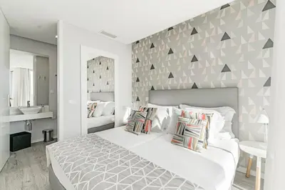 a bedroom with a large white bed with a wall with triangles at FAA Rentals 31 de Janeiro by An Island Apart in Funchal