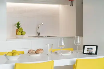 a kitchen with yellow chairs and a table with food and wine glasses at FAA Rentals 31 de Janeiro by An Island Apart in Funchal