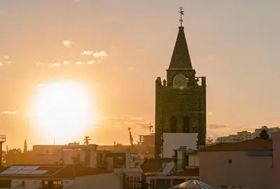 a church steeple with a clock tower in a city at FAA Rentals 31 de Janeiro by An Island Apart in Funchal