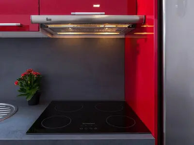 a kitchen with a black stove and red cabinets at Casa Silva in Calheta