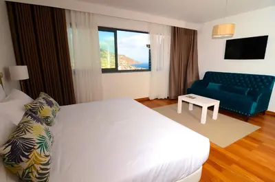 a bedroom with a white bed and a blue couch at Casas do Forte do Pico in Funchal
