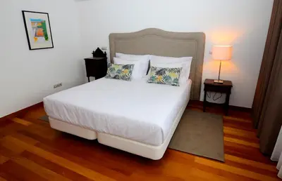 a bedroom with a large white bed with a headboard at Casas do Forte do Pico in Funchal
