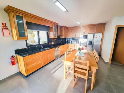 a kitchen with a wooden table and wooden cabinets at House of Massapez | Calheta in Fajã da Ovelha