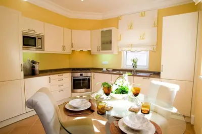 a kitchen with a glass table and white cabinets at Luxury One Bedroom Palheiro Village by Holiday Rental Madeira in Funchal