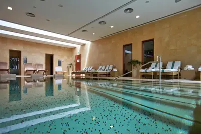a swimming pool in a hotel with white chairs at Luxury One Bedroom Palheiro Village by Holiday Rental Madeira in Funchal