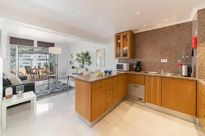 a kitchen with wooden cabinets and a living room at Arriaga I by An Island Apart in Funchal