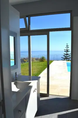 a bathroom with a sink and a view of the ocean at Casa do Lado in Ponta do Sol
