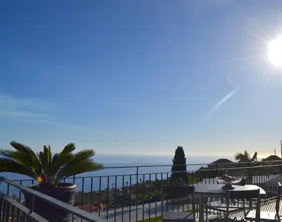 a balcony with a table and chairs and the ocean at Casa do Lado in Ponta do Sol