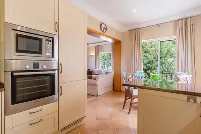 a kitchen with a microwave and a living room at Luxury two bedroom Palheiro Village by Holiday Rental Madeira in Funchal