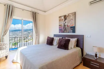 a bedroom with a large bed and a large window at Luxury two bedroom Palheiro Village by Holiday Rental Madeira in Funchal