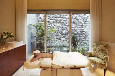 a woman laying on a bed in a room with a window at Luxury two bedroom Palheiro Village by Holiday Rental Madeira in Funchal
