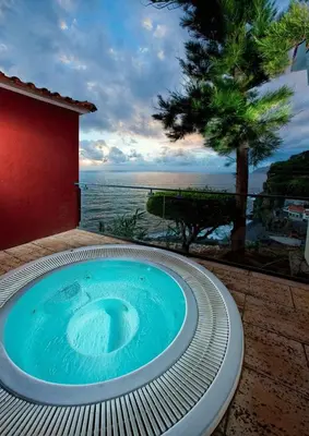 a hot tub on a patio with a view of the ocean at Estalagem Da Ponta Do Sol in Ponta do Sol