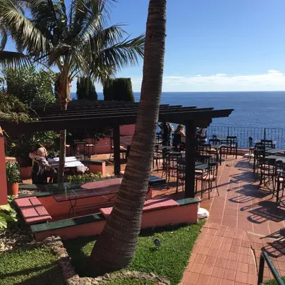 a patio with tables and chairs and the ocean at Inn & Art Madeira in Caniço