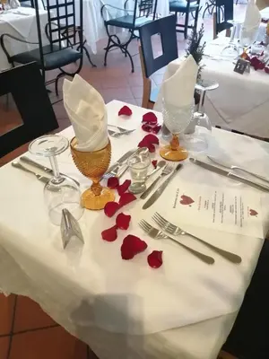 a table with red flowers on a white table cloth at Inn & Art Madeira in Caniço