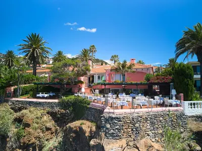a resort with tables and chairs and palm trees at Inn & Art Madeira in Caniço