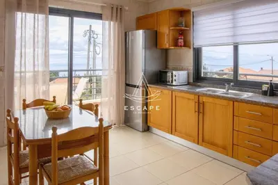 a kitchen with a table and a large window at Vila Sol in Prazeres