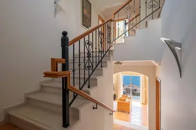 a staircase in a home with white walls and wooden railings at Designed Villa Palheiro Village by Holiday Rental Madeira in Funchal