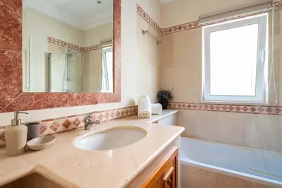 a bathroom with a sink and a tub and a mirror at Designed Villa Palheiro Village by Holiday Rental Madeira in Funchal