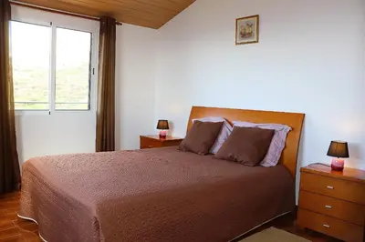 a bedroom with a bed with two night stands and a window at Casa Bela Vista in Ribeira Brava