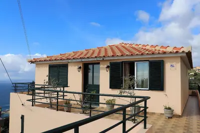 a small house with black shutters on a balcony at Casa Bela Vista in Ribeira Brava