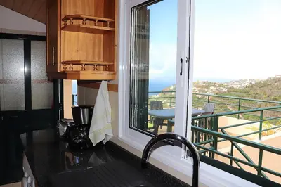 a kitchen with a window with a view of a balcony at Casa Bela Vista in Ribeira Brava